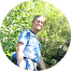 Un homme en chemise bleue se tient debout dans un cercle avec des arbres en arrière-plan.