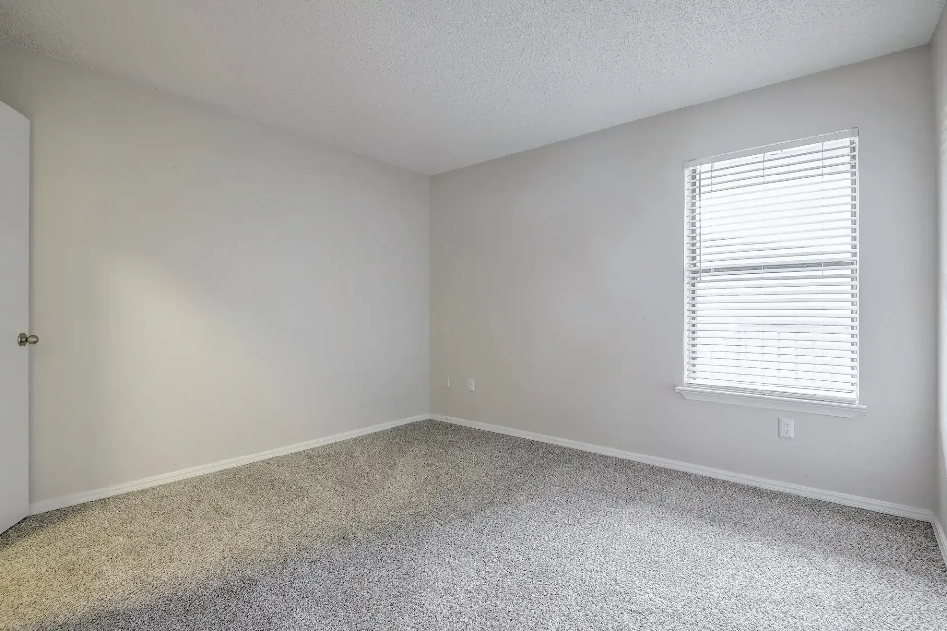 An empty bedroom with a walk in closet and a carpeted floor.
