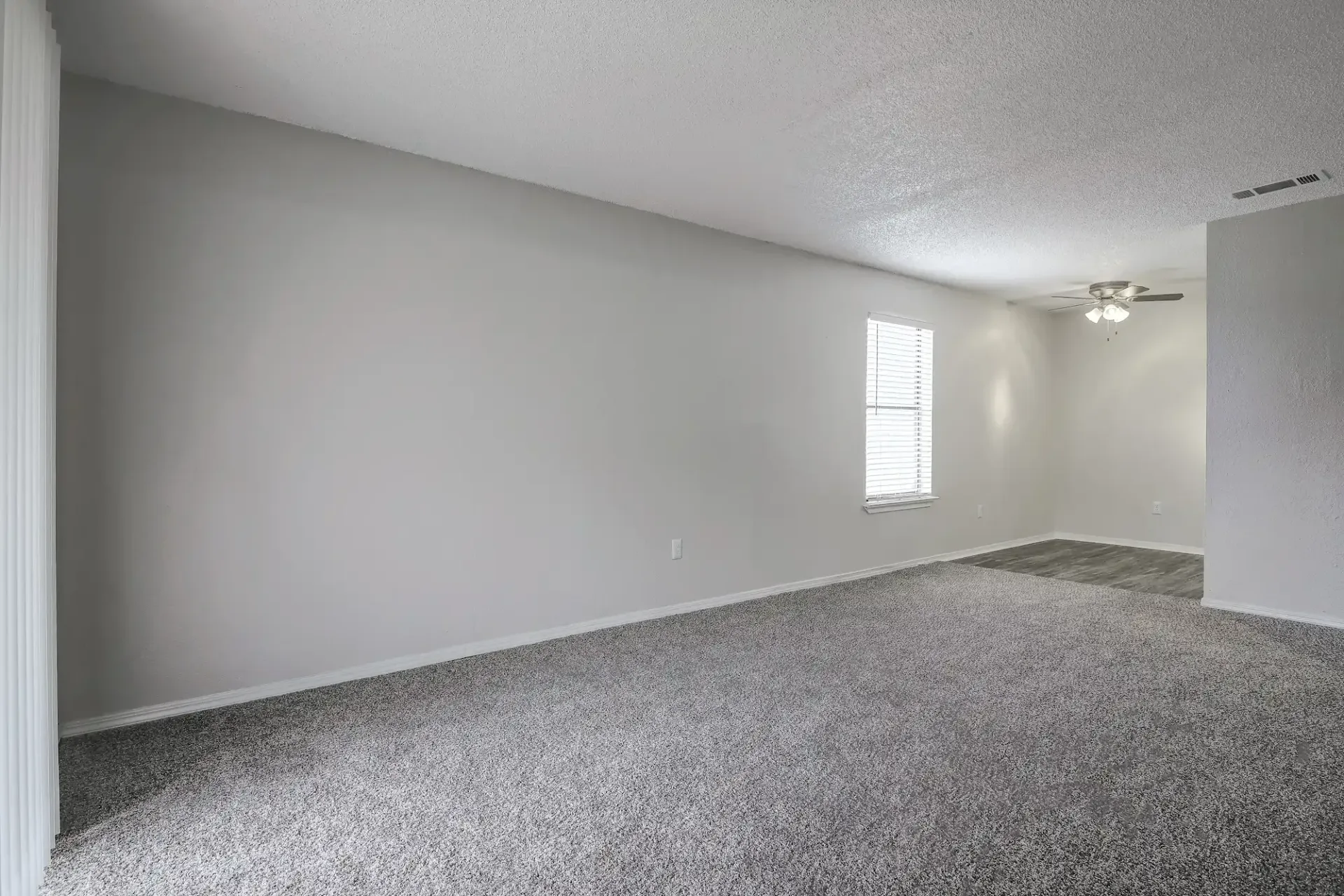 An empty bedroom with a carpeted floor and a closet.