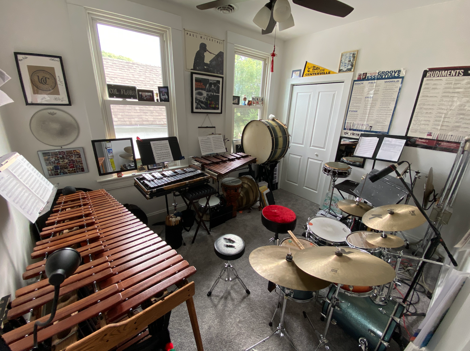 Music rehearsal room filled with percussion instruments, keyboards, and sheet music near bright windows