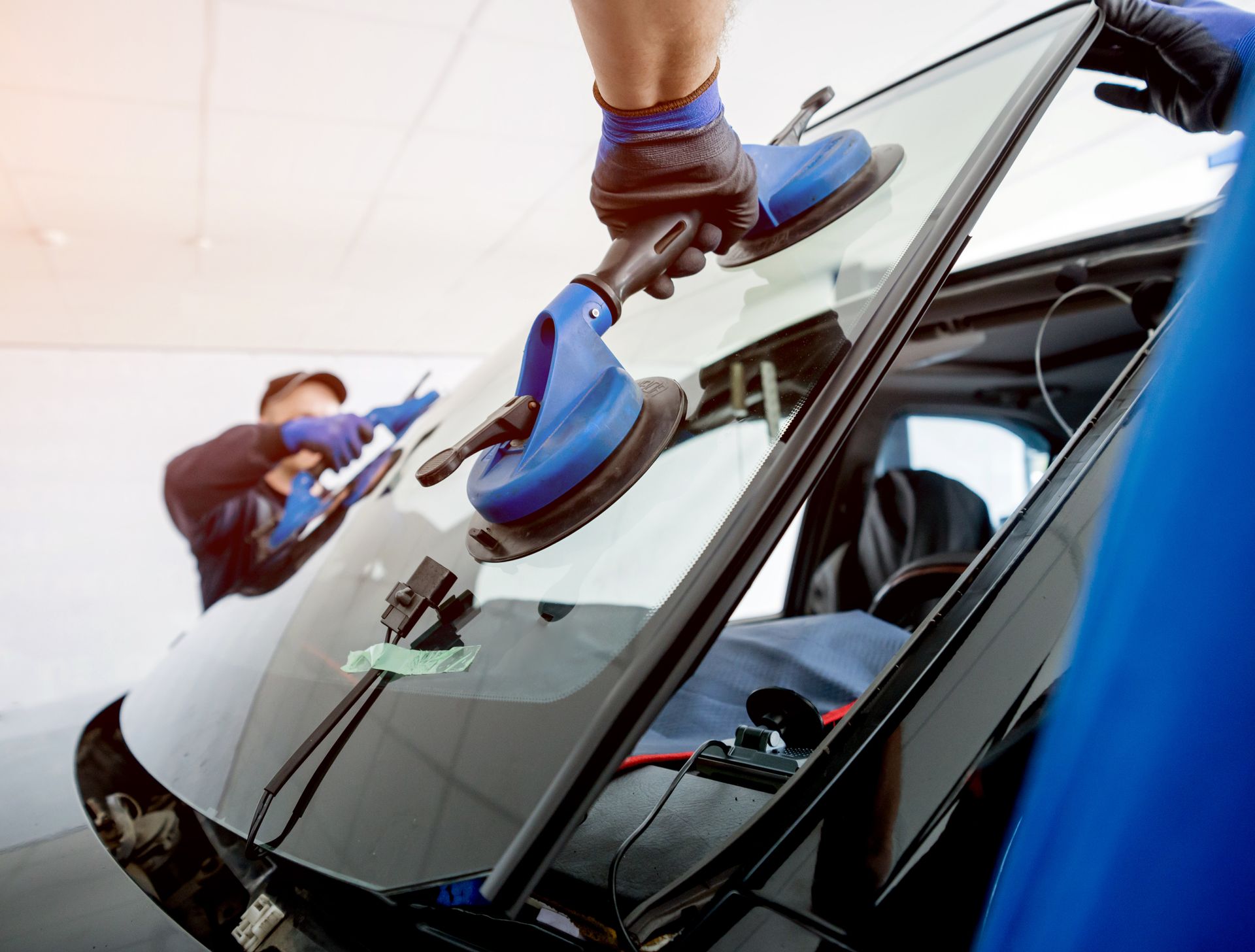 Automobile workers replacing car windshield.