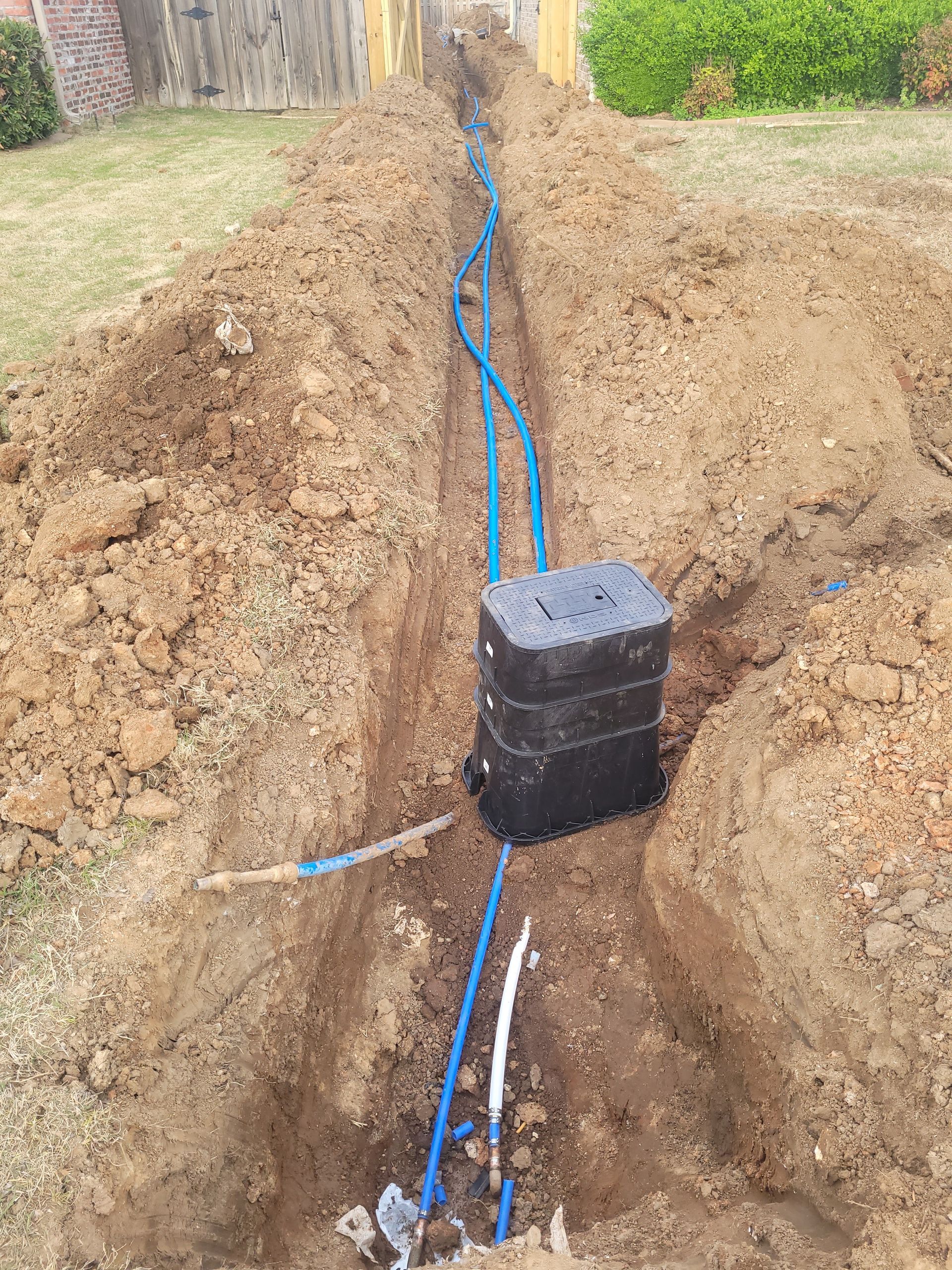 A hole in the ground with blue pipes coming out of it.