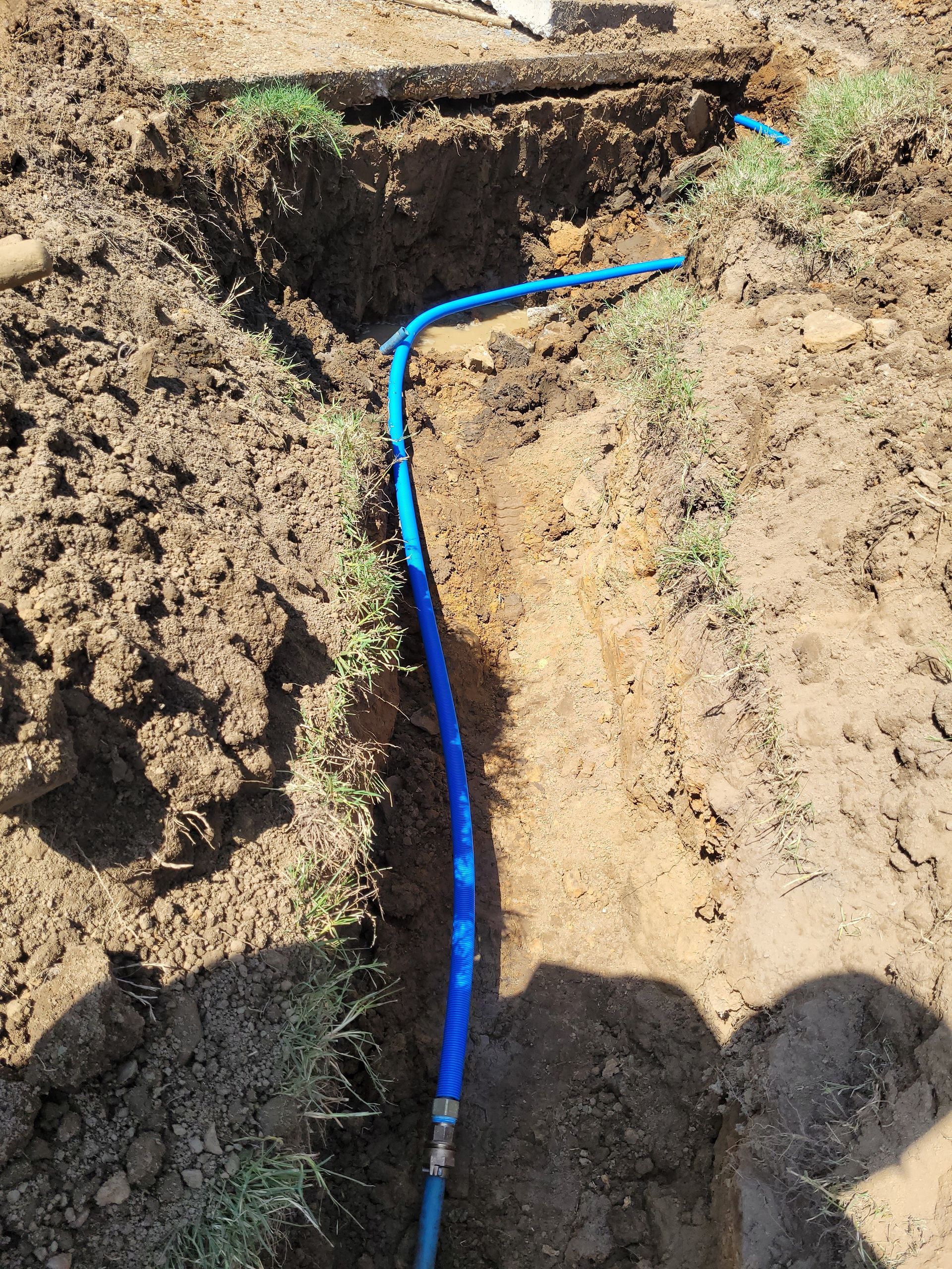 A blue pipe is being installed in the dirt.