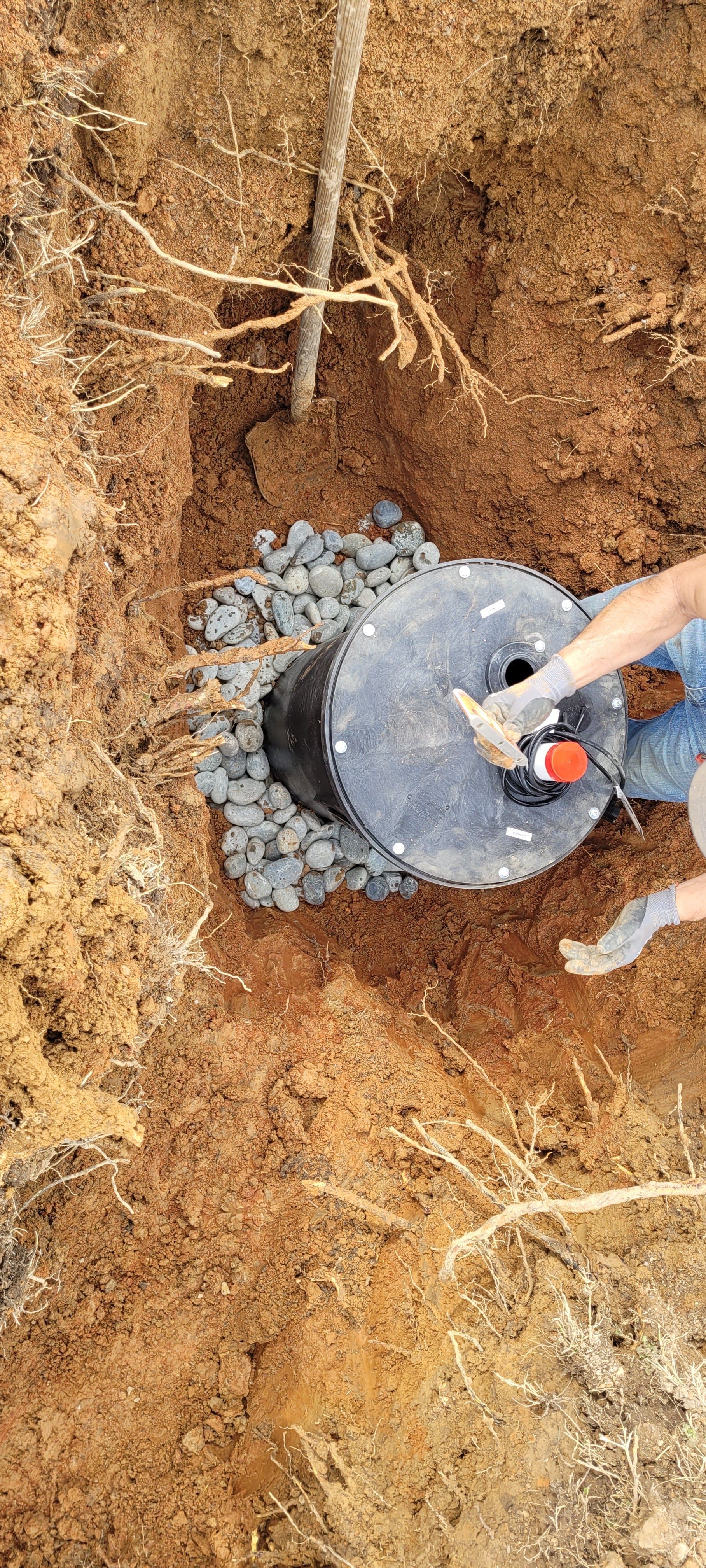 A person is digging a hole in the ground to install a septic tank.