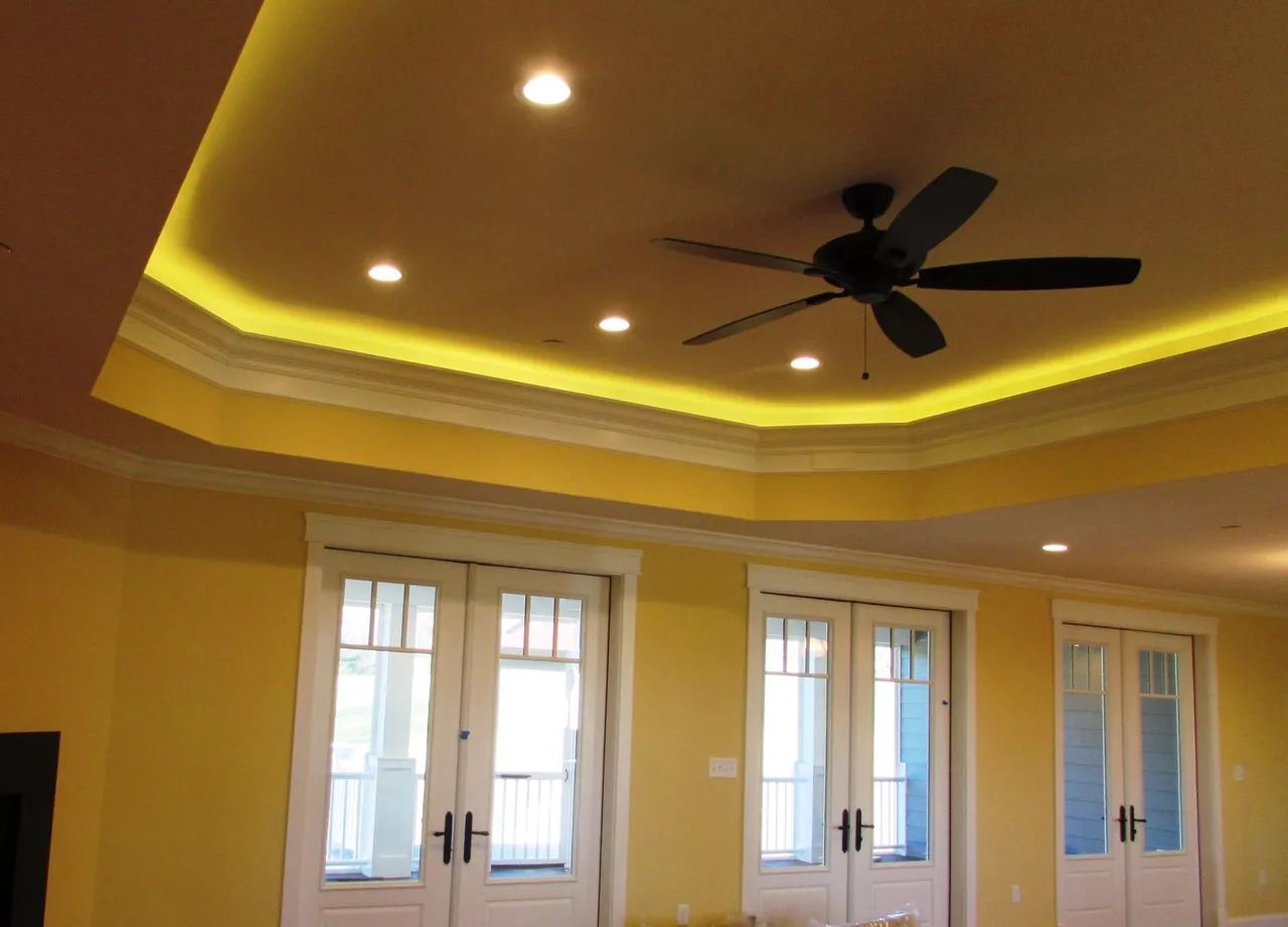 A living room with yellow walls and a ceiling fan