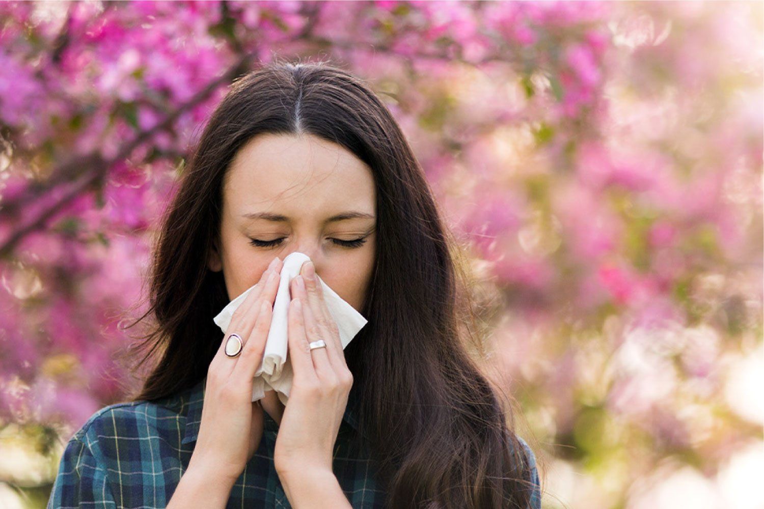 woman standing outside blowing nose