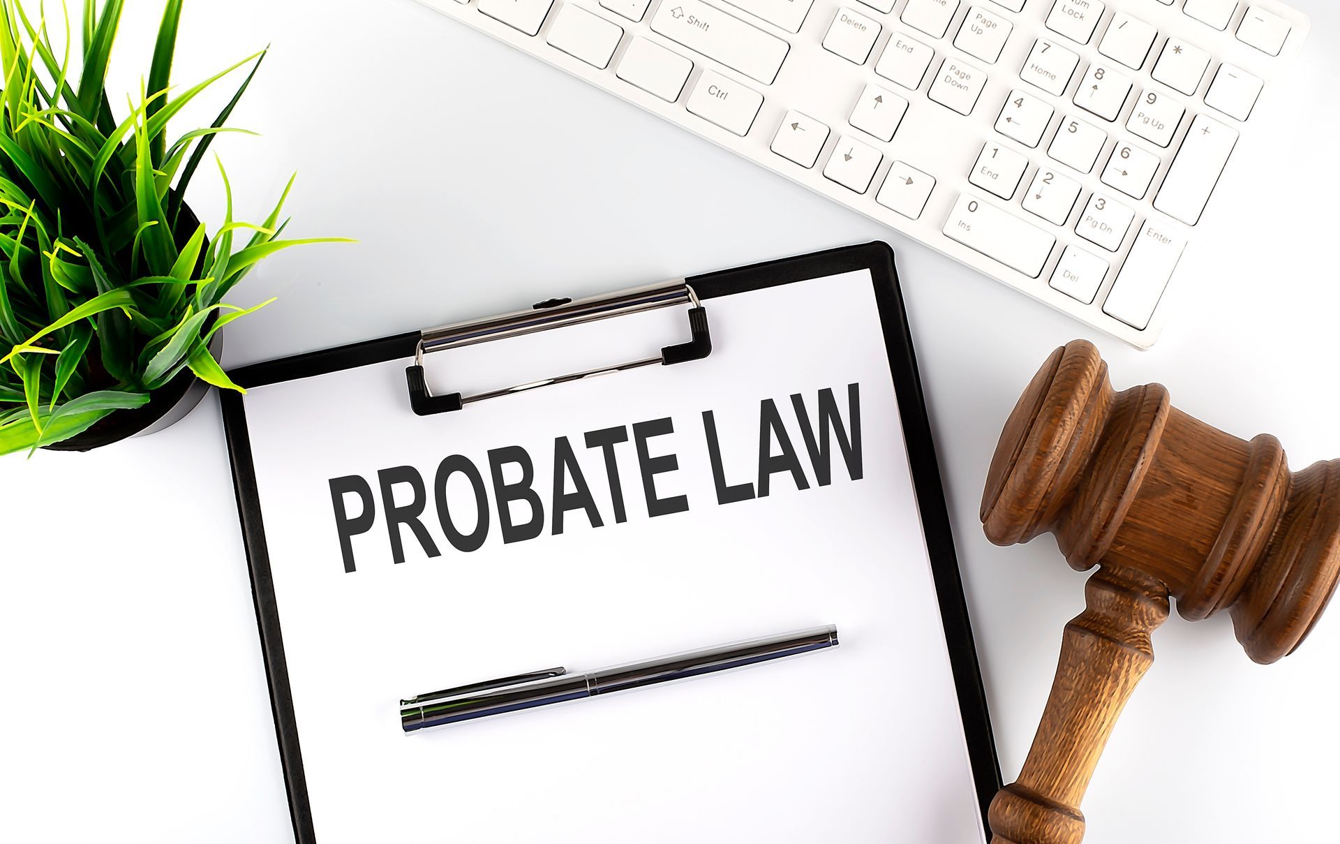 Probate law clipboard with pen, gavel, keyboard and plant on white desk for legal services concept.