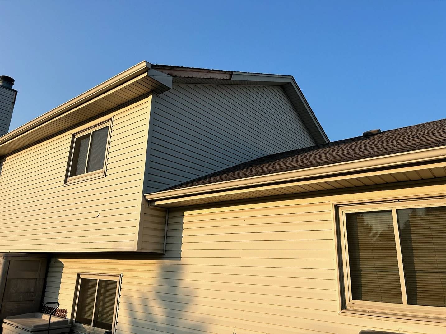 Beige two-story house with brown roof and windows in sunlight