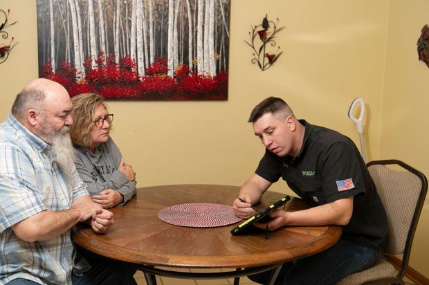 A man is sitting at a table talking to two people.