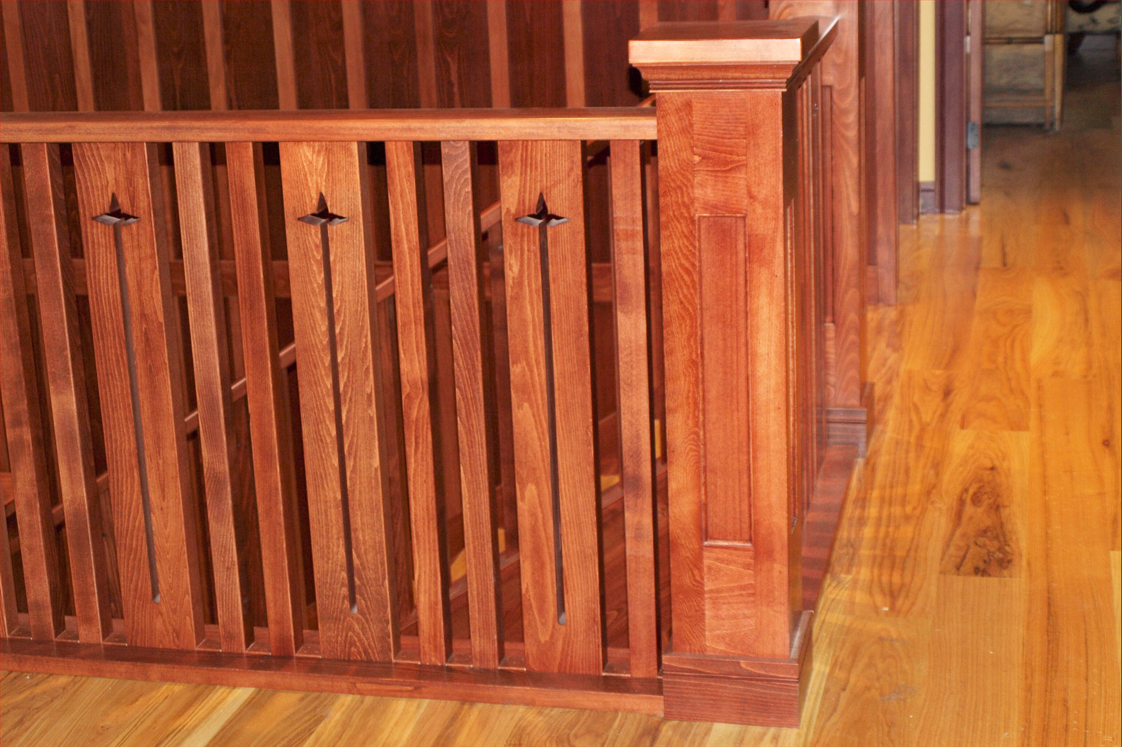 Wooden staircase railing with star-shaped cutouts, warm wood tone, indoors.