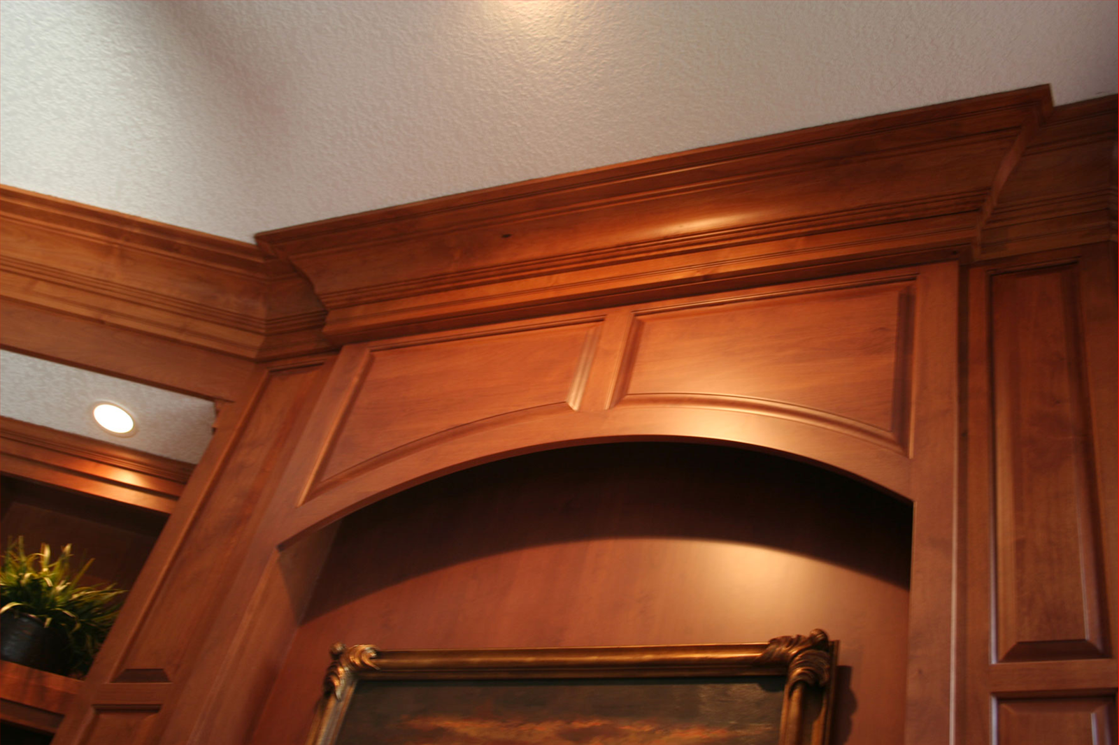 Wooden cabinet with arched opening and decorative trim, illuminated by a warm light.