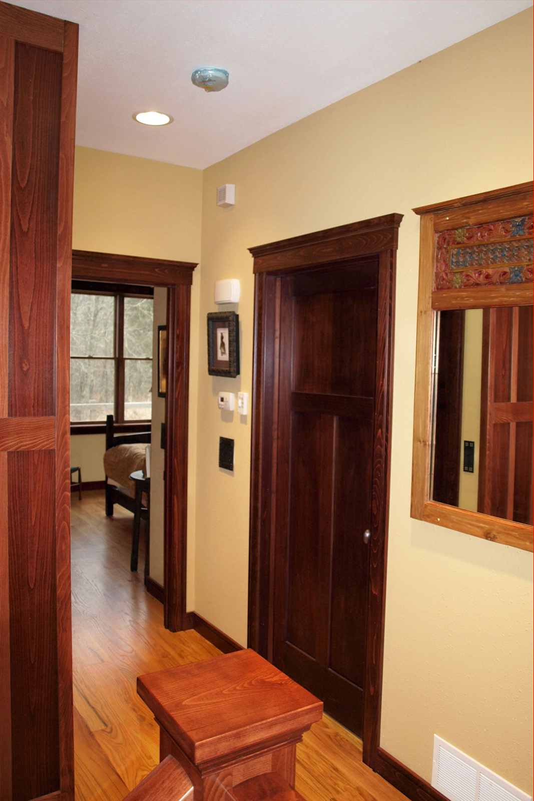 Hallway with wooden doors, trim, and light yellow walls. A square wooden table is at the bottom.