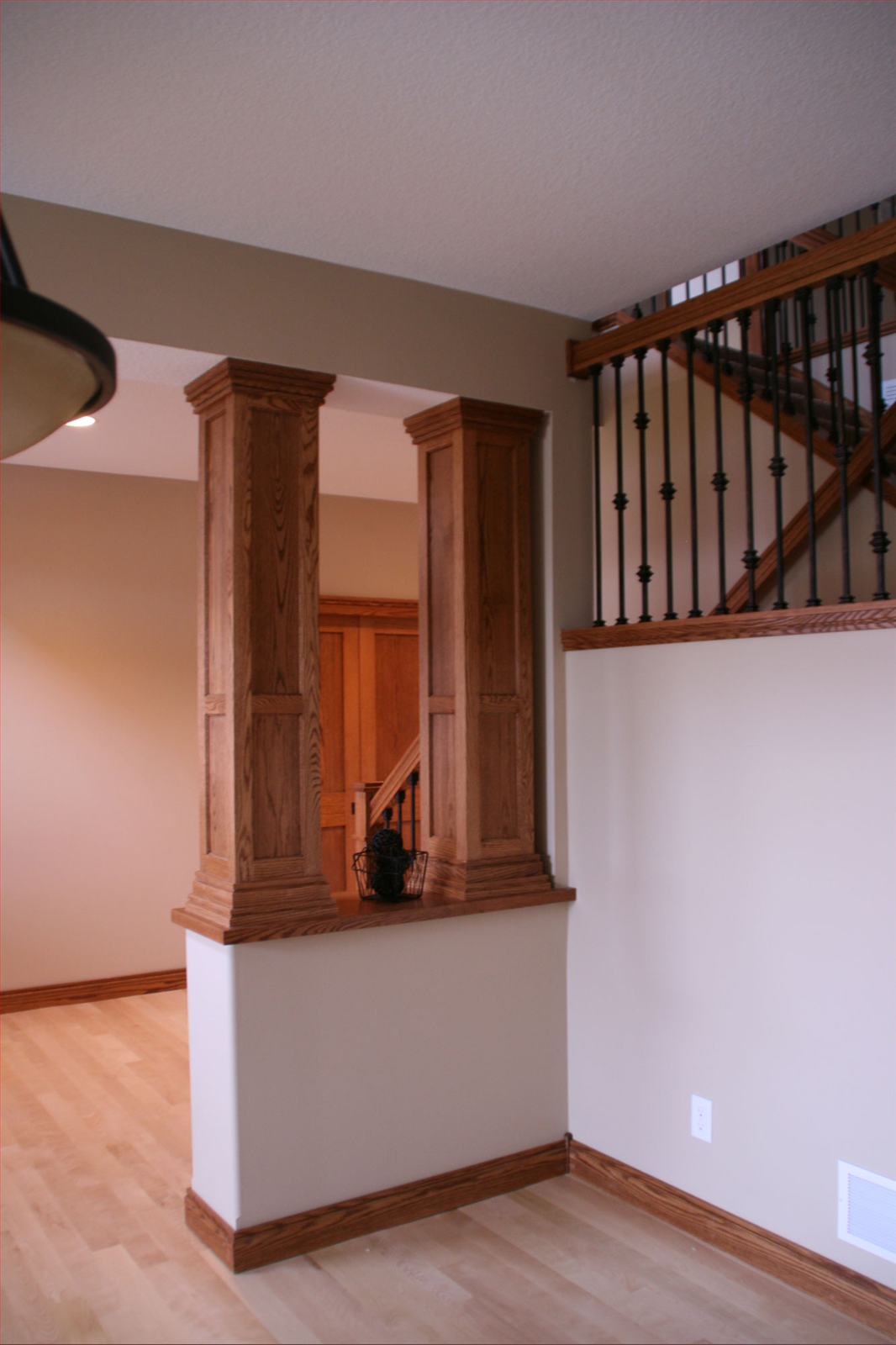Interior with wood columns, staircase, beige walls, and wood trim.