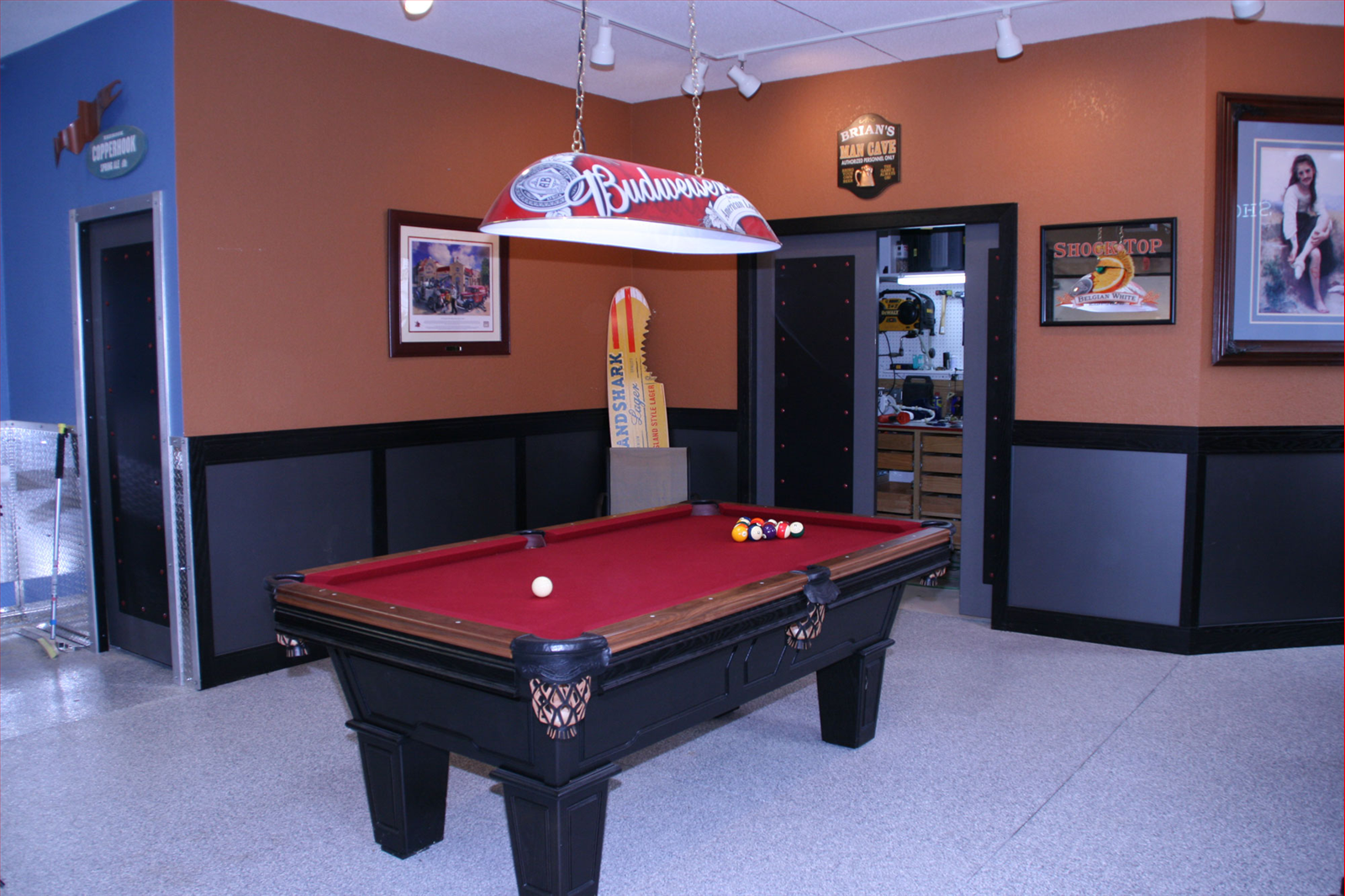 Pool table in a room with brown and blue walls, artwork, and a hanging light fixture.