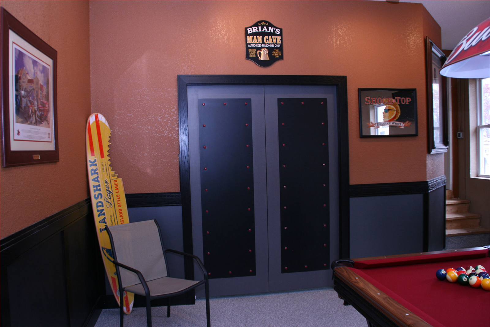 A finished basement with a pool table, double doors, and sports memorabilia.
