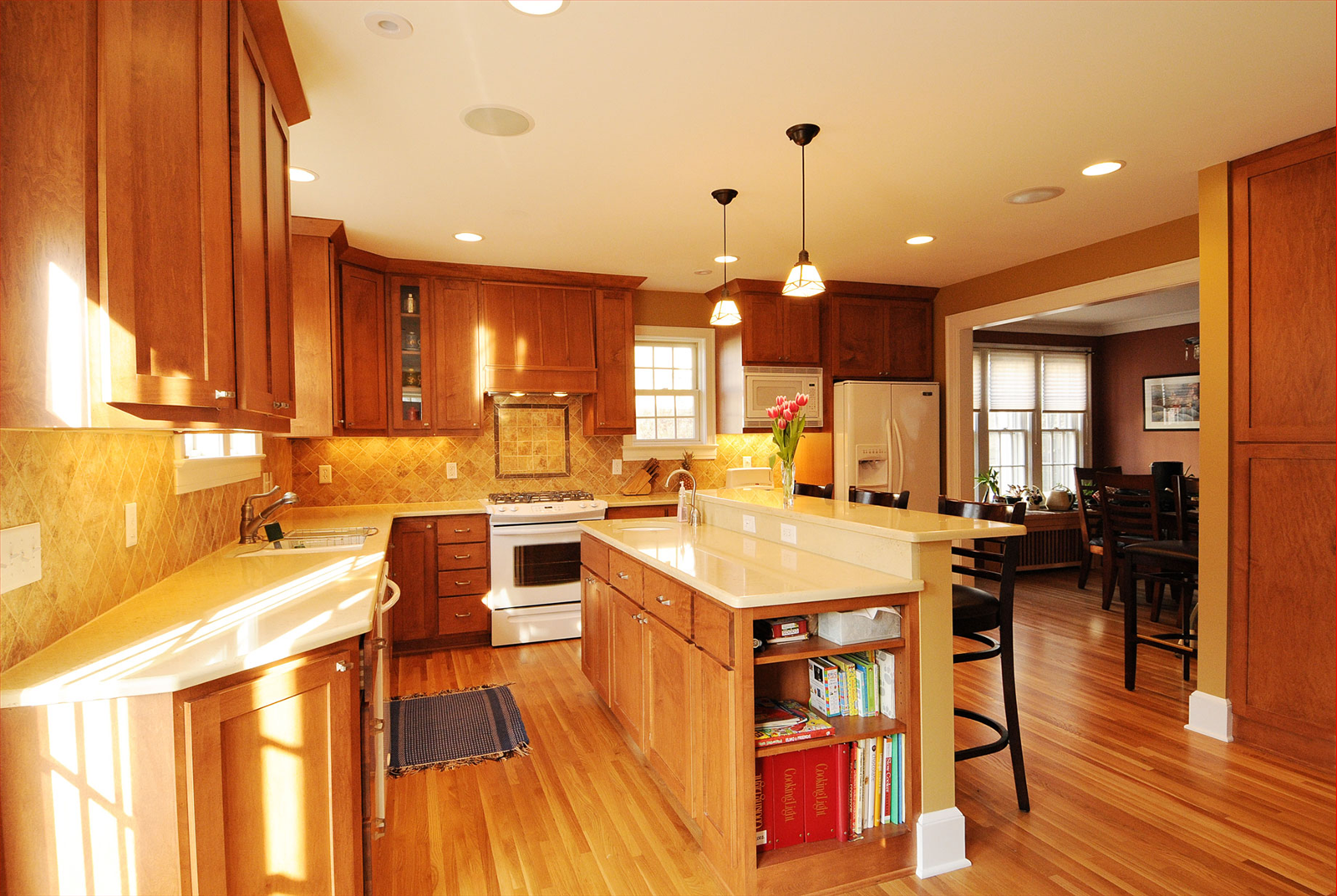 Warm-toned kitchen with wooden cabinets and island, a stove, and open doorway to dining area.