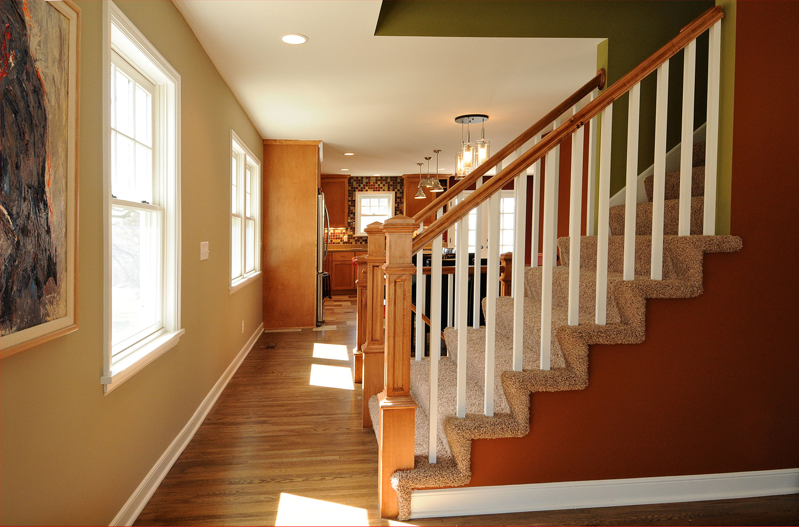 Hallway with staircase, windows, and brown and green walls.