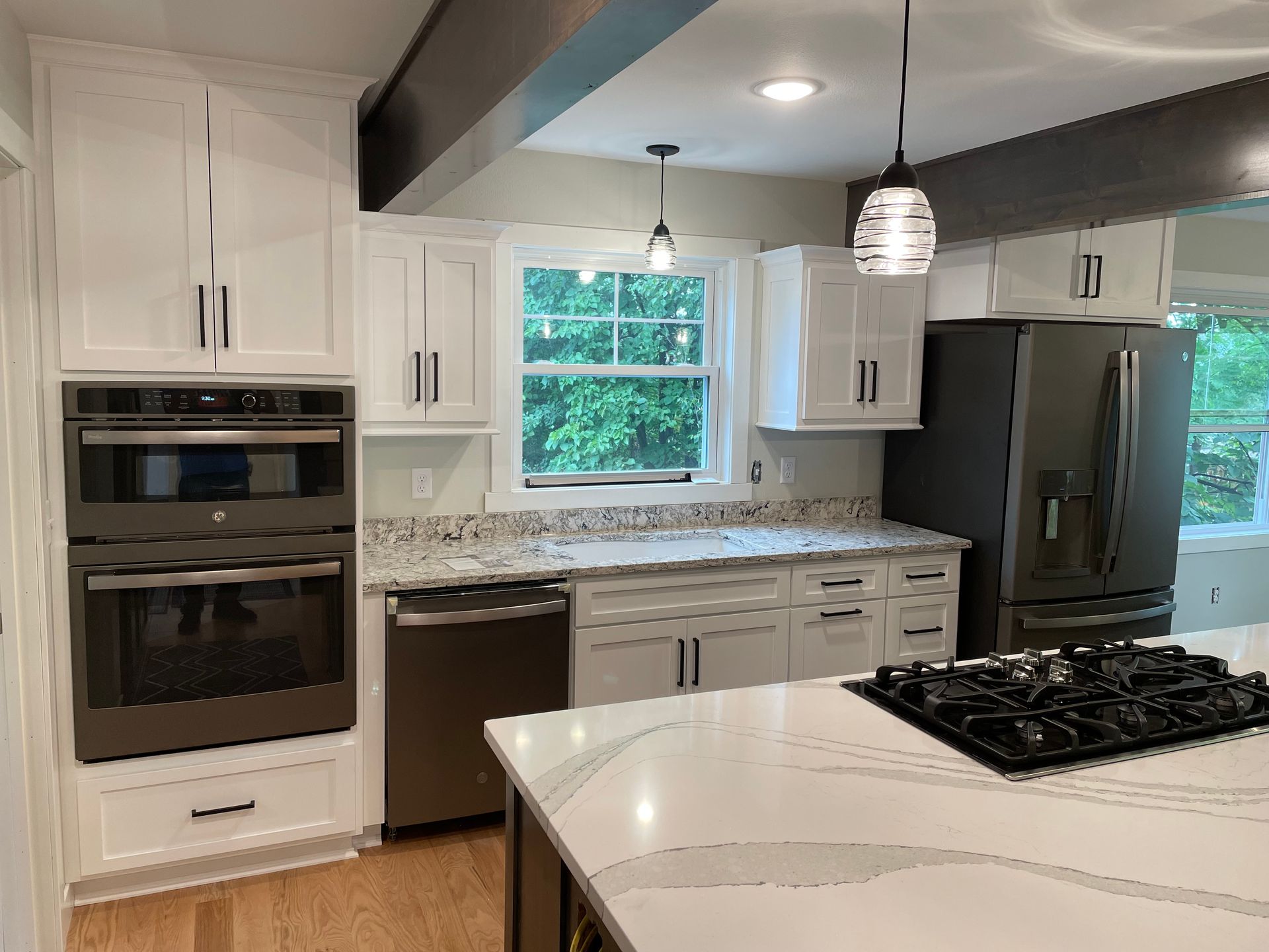 Modern kitchen with white cabinets, stainless steel appliances, and a gas cooktop on an island.