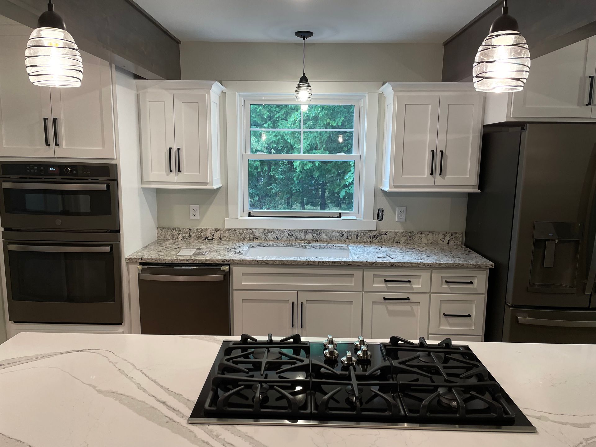 White kitchen with cabinets, stainless steel appliances, and a gas cooktop on an island.