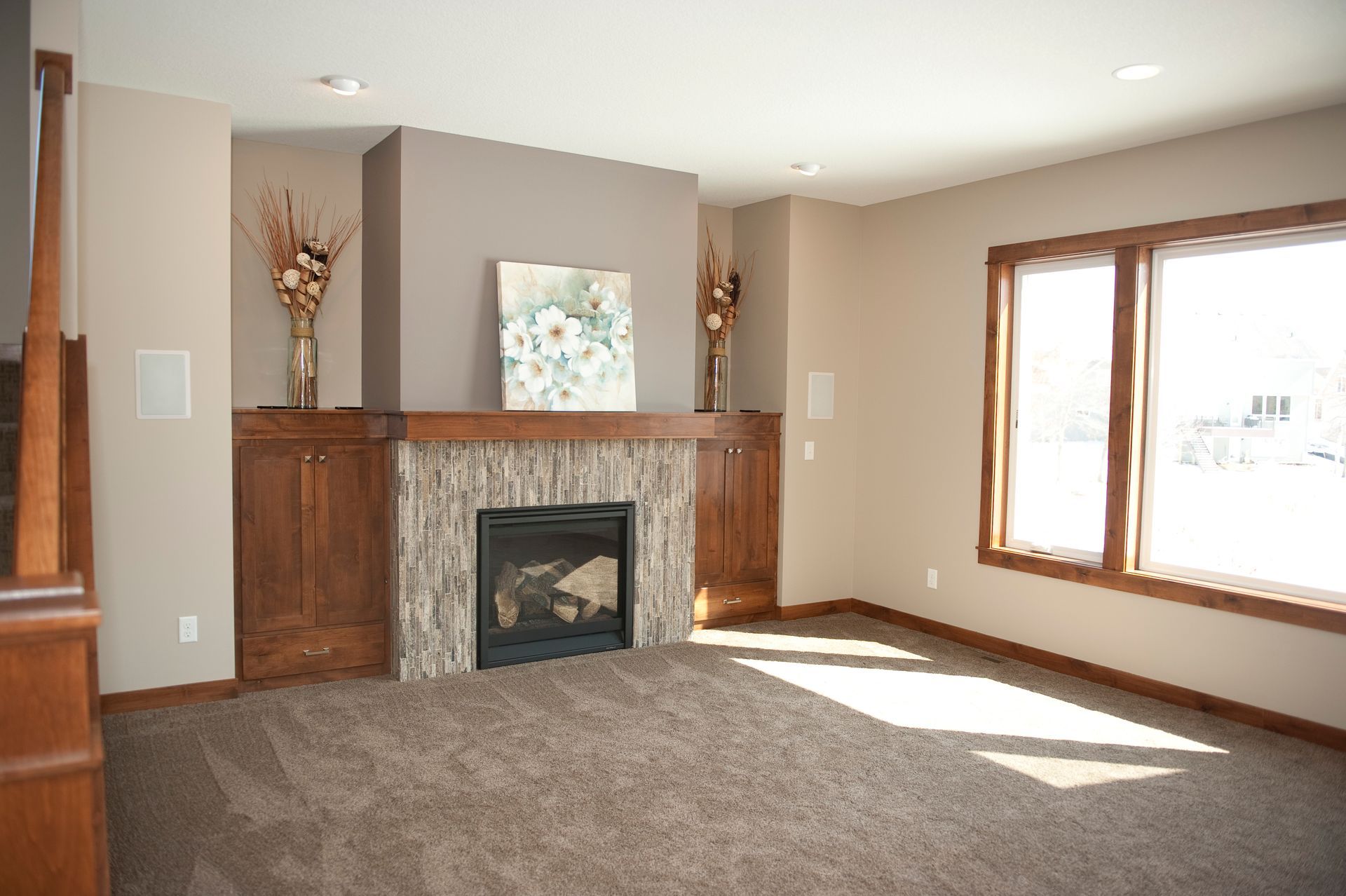 Living room with fireplace, built-in cabinets, carpet, and large windows. Brown and beige tones.