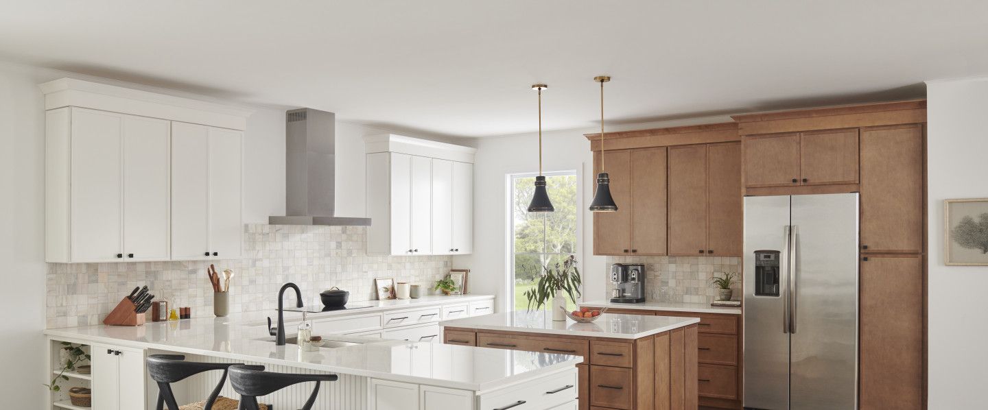 A modern kitchen with white and brown cabinets, an island, and stainless steel appliances.