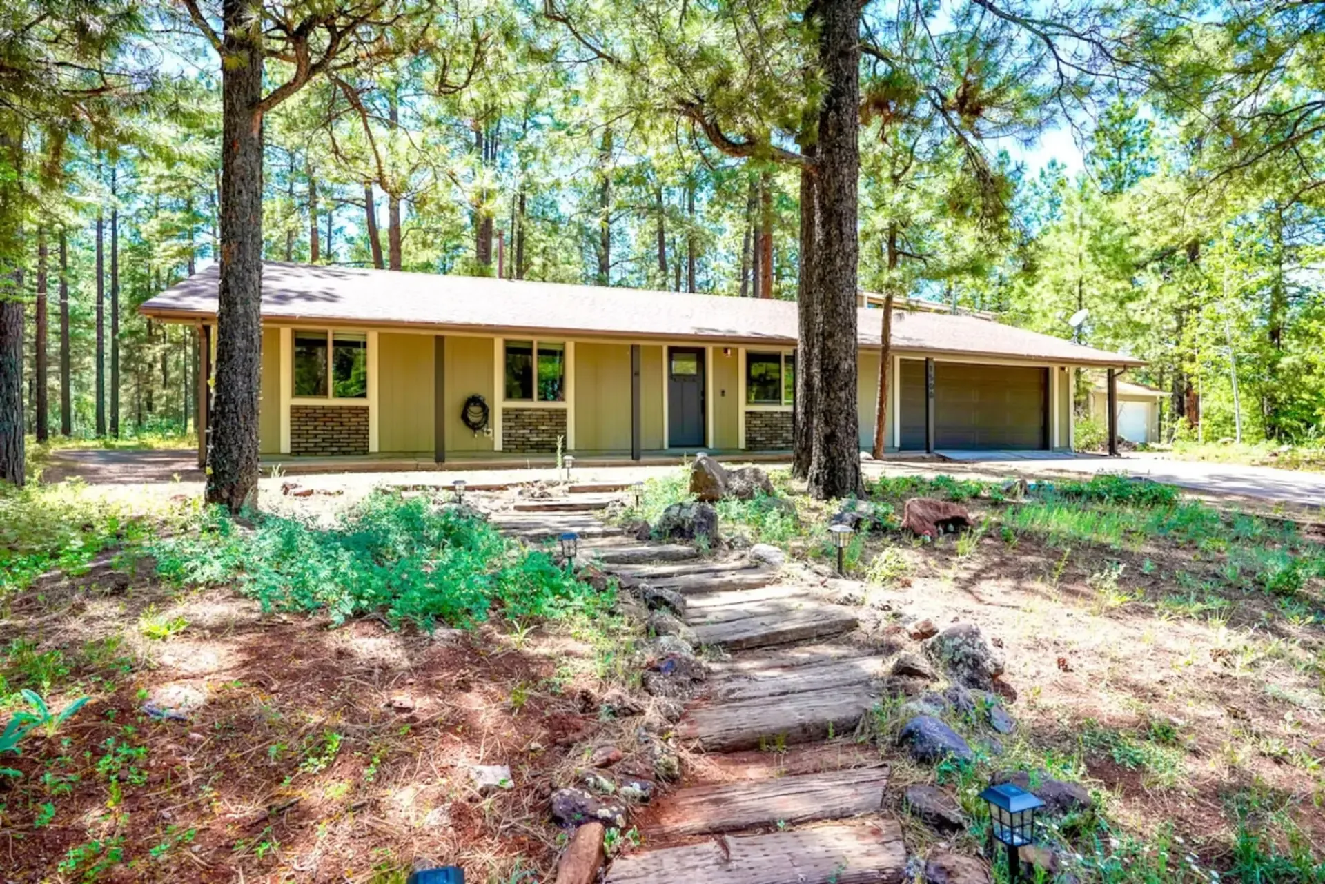 Eagle’s Nest vacation home among tall pine trees in Flagstaff, with a stone path leading to the front porch.