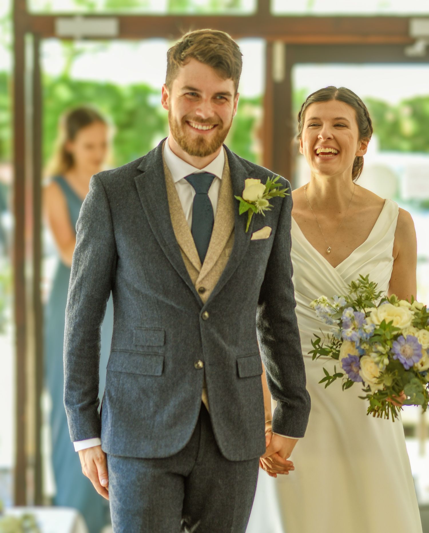 smiling bride and smiling groom walking into their wedding reception at bournemouth