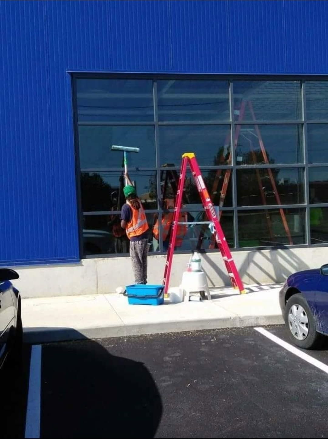 A man is cleaning the windows of a building next to a ladder
