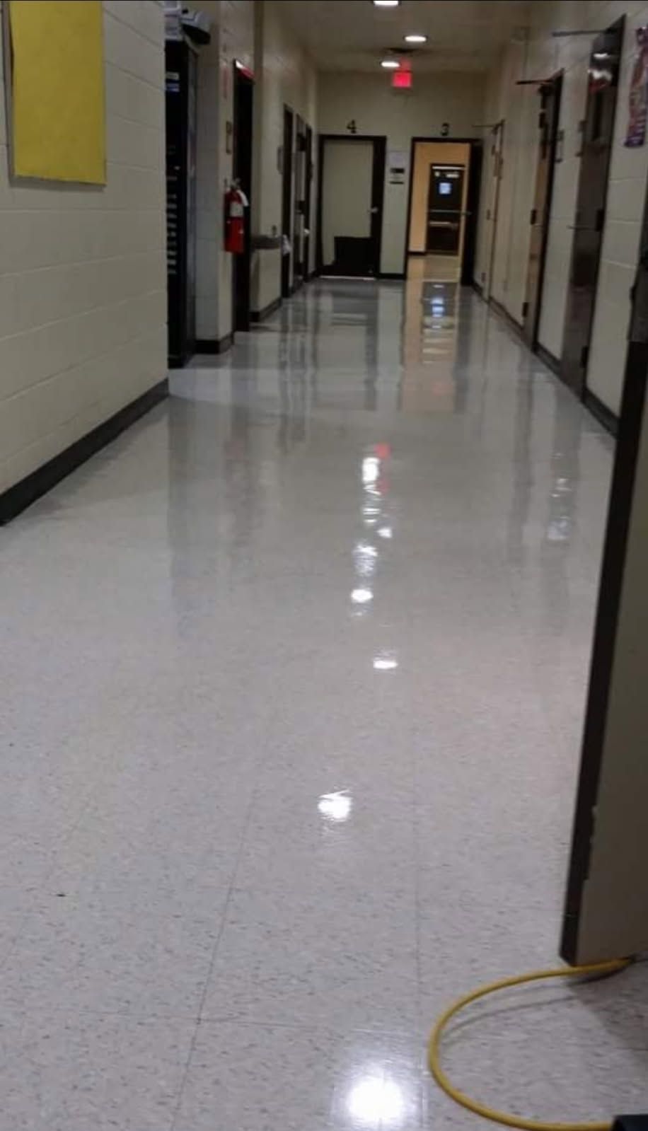 A long hallway with a lot of doors and a yellow cord.