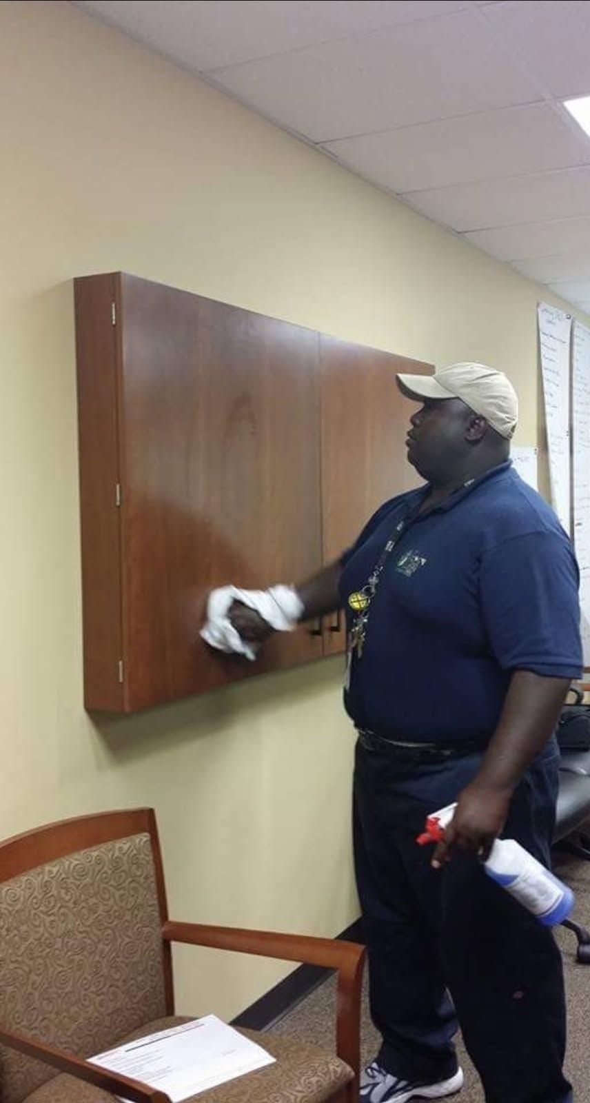 A man is cleaning a wall with a towel and spray bottle.