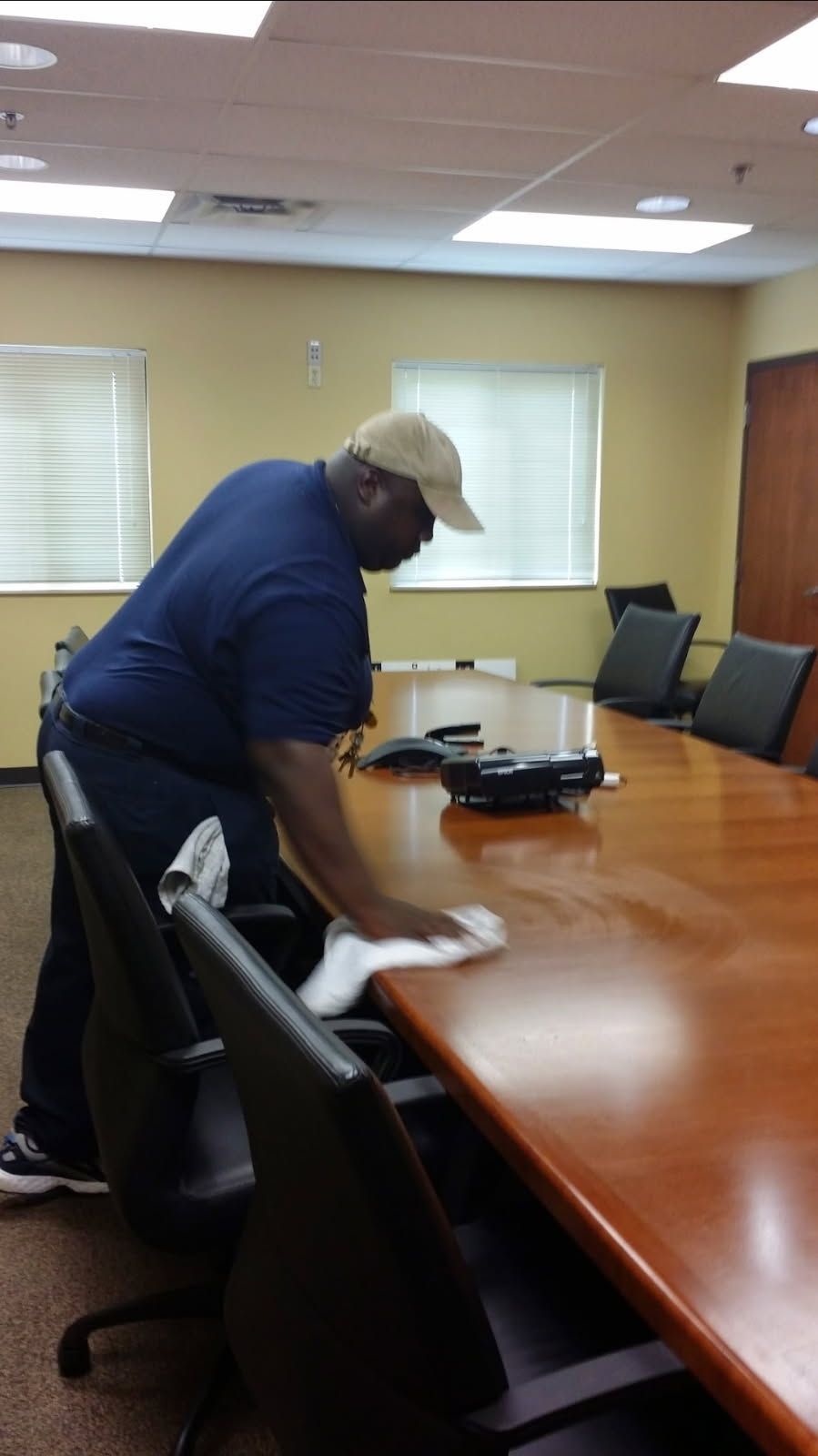 A man is cleaning a conference room table with a cloth