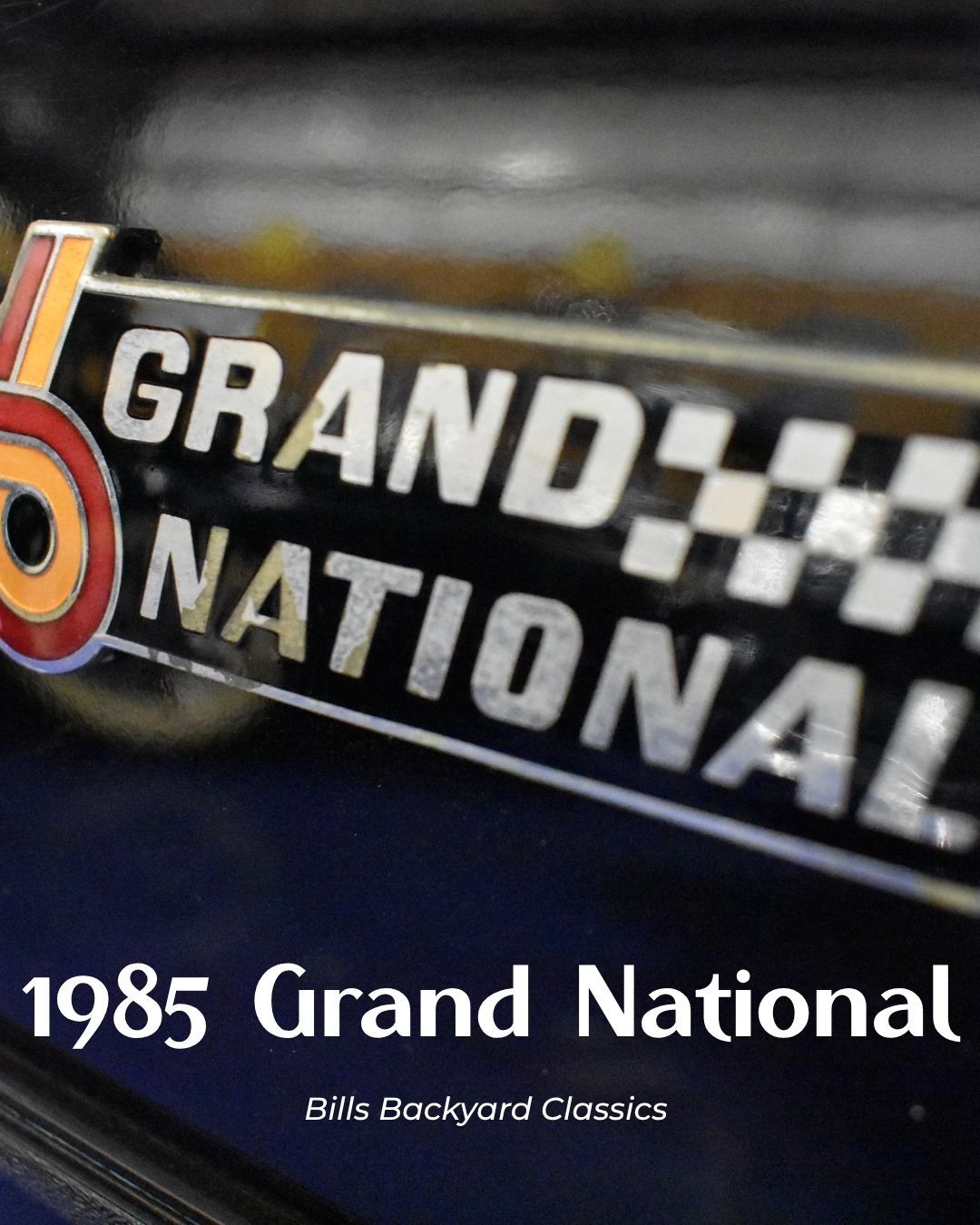 Close-up of a 1985 Grand National emblem with checkered flag detail.