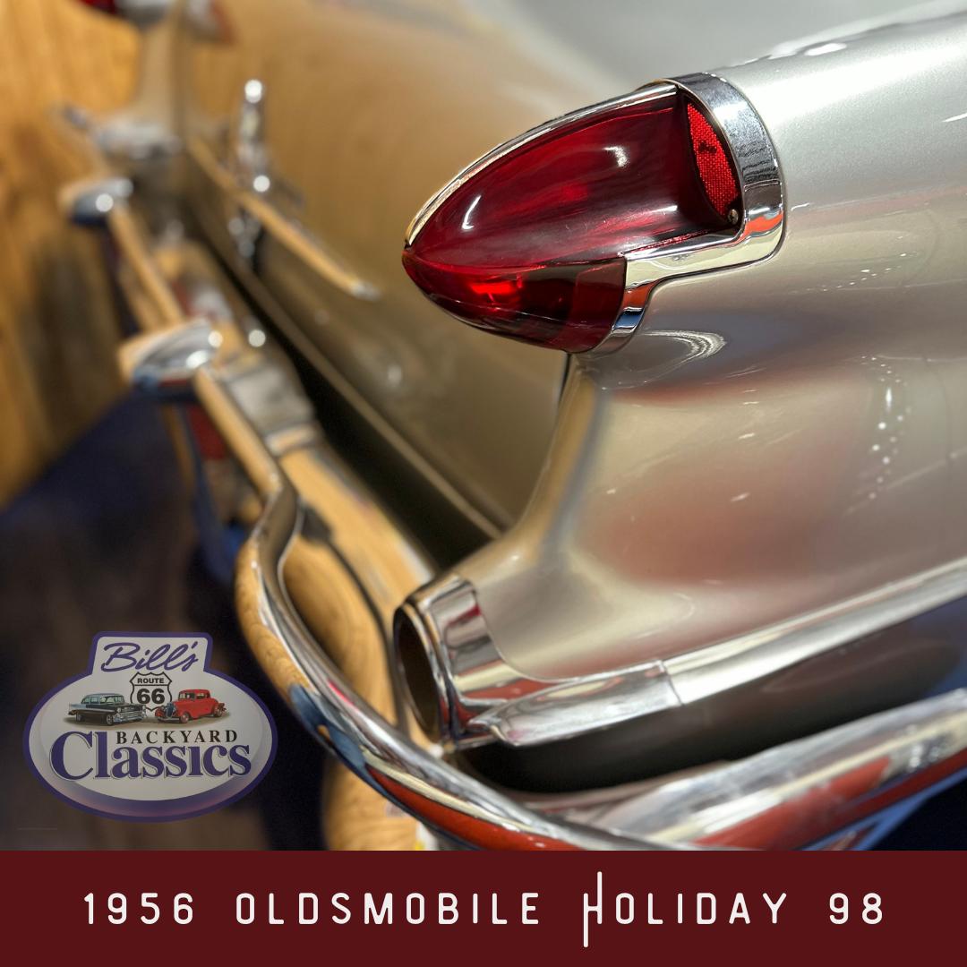 Close-up of a silver 1956 Oldsmobile Holiday 98's tail fin and taillight.