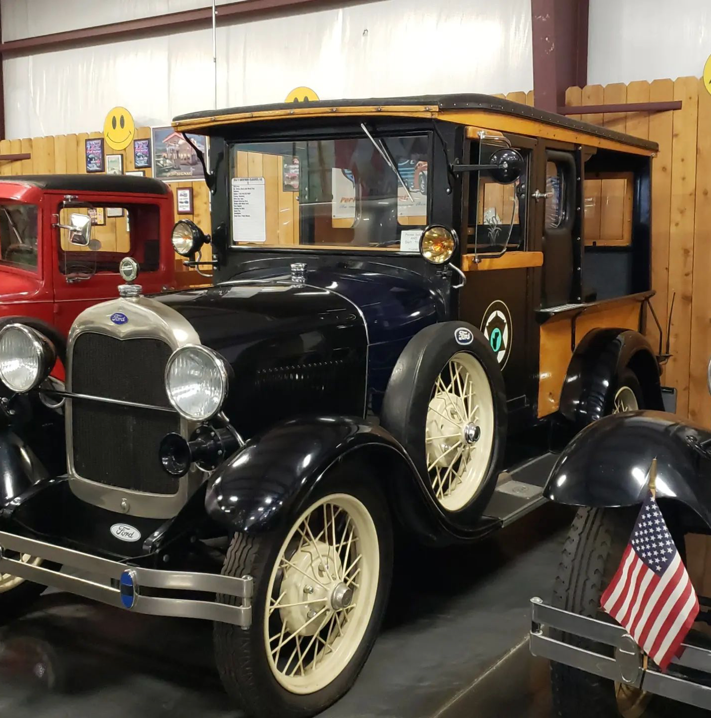 Black and blue vintage Ford Model A pickup truck with white wheels, displayed indoors.