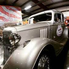 Silver vintage truck with large headlights, parked indoors.