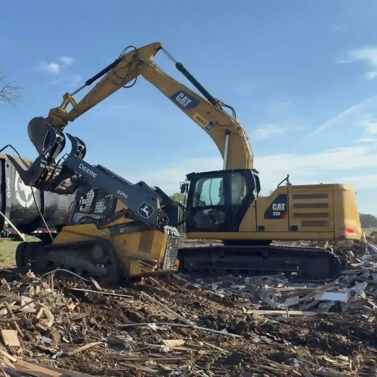 Yellow excavator crushing debris in a rubble-strewn demolition site under a blue sky