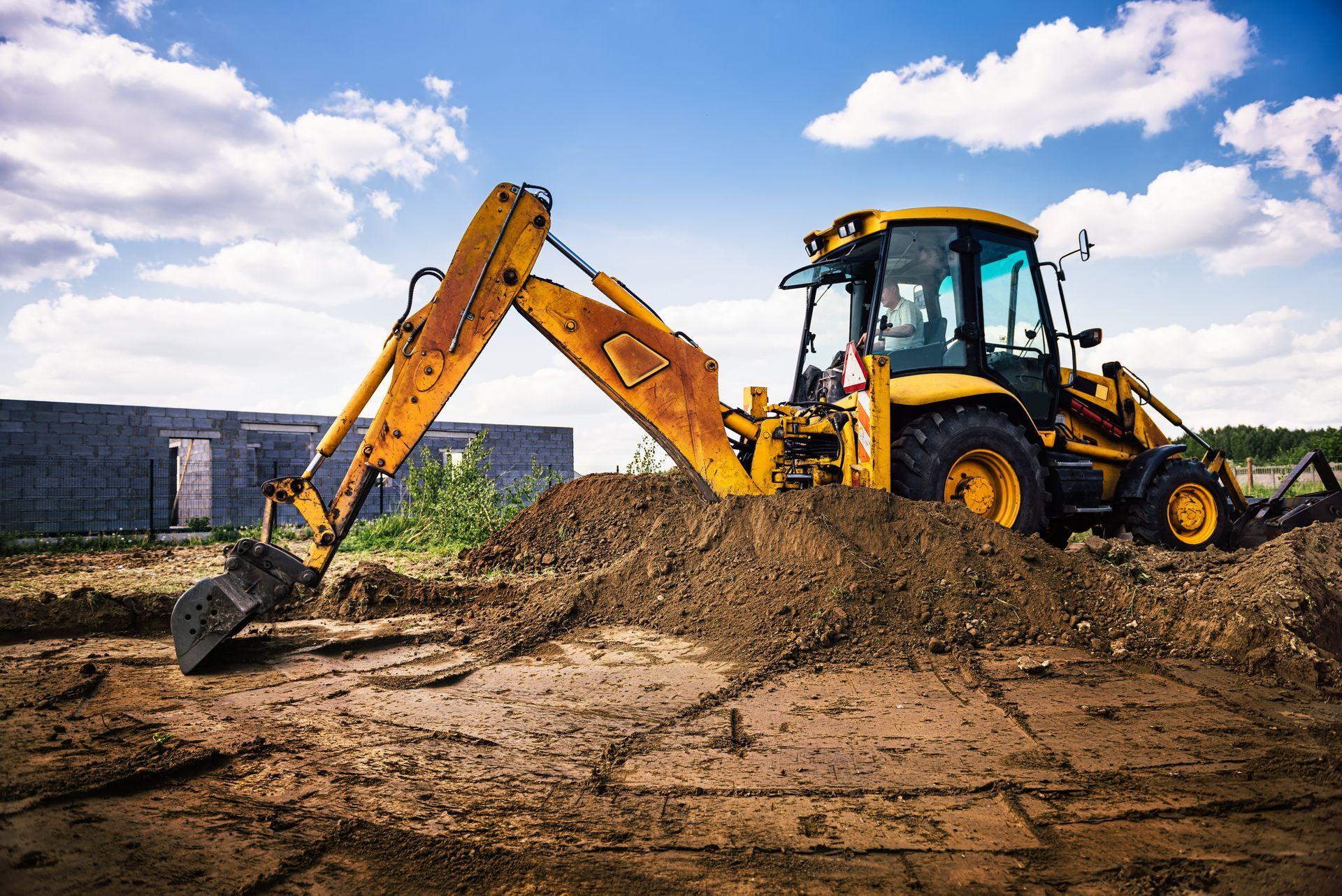 Yellow excavator and backhoe loader moving dirt at a construction site under a blue sky