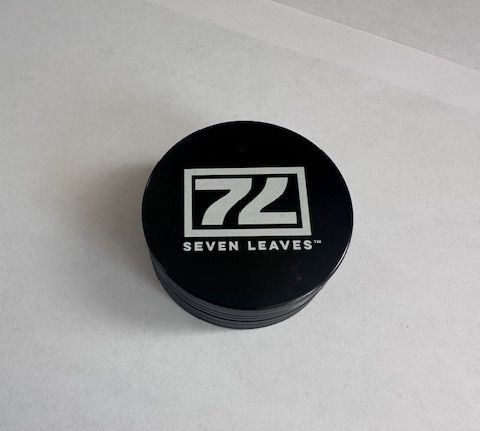 Black Seven Leaves herb grinder on a white surface.
