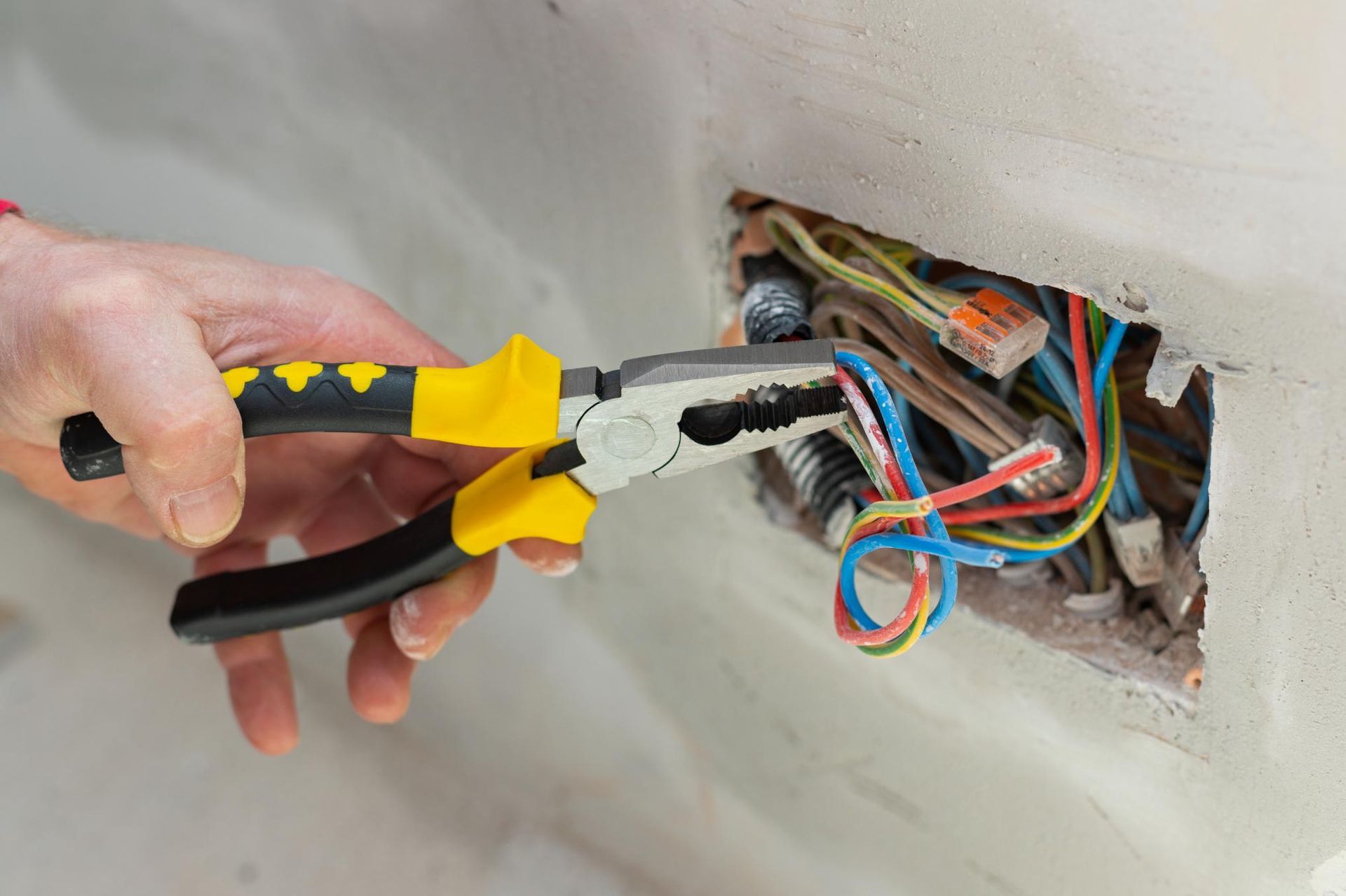 A Person Is Working on An Electrical Outlet with Pliers — Cairns & Cape Electrical In Woree, QLD