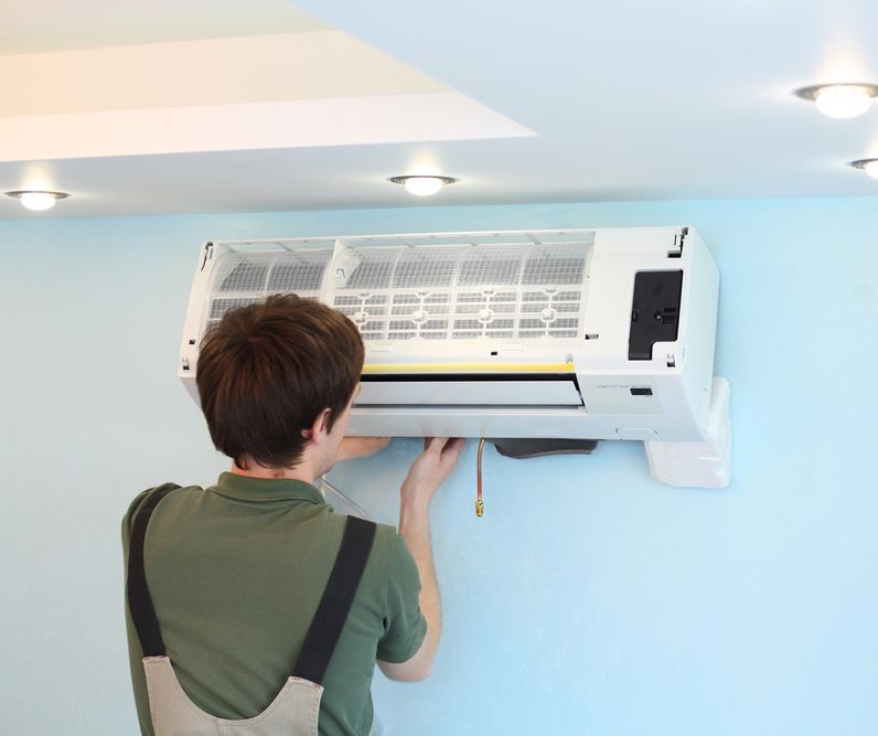 Man Installs Air Conditioner In The Room — Cairns & Cape Electrical In Woree, QLD