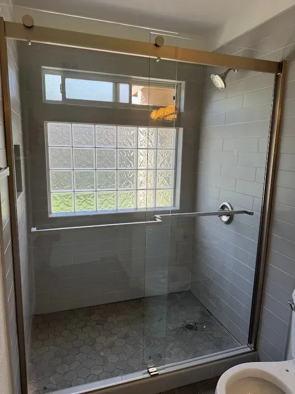 A bathroom with a sliding glass shower door and a toilet.