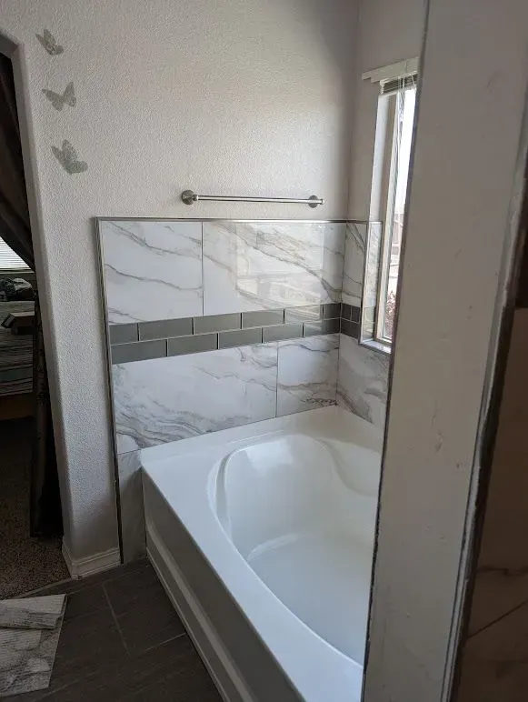 A bathroom with a bathtub and a window.