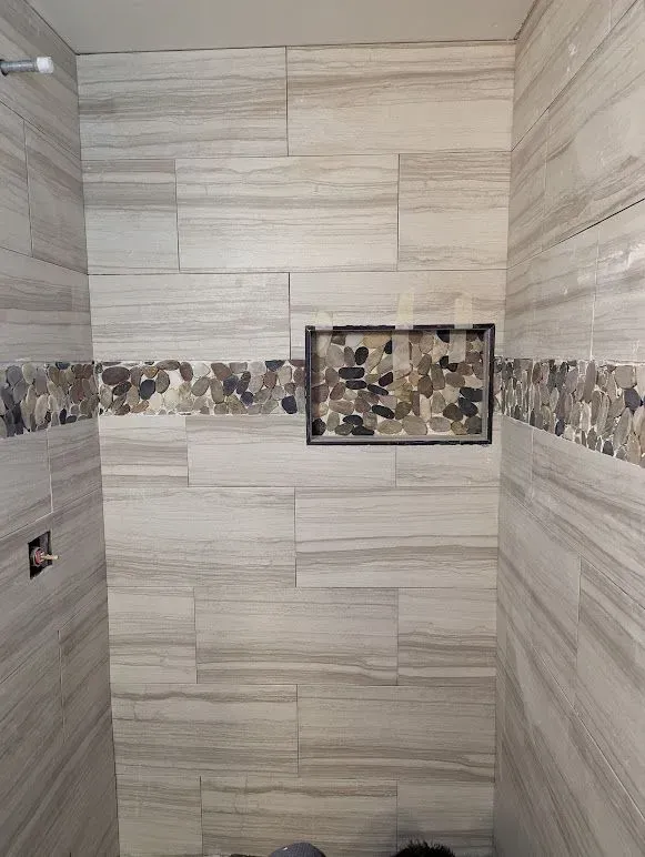A bathroom with a shower and a tiled wall.