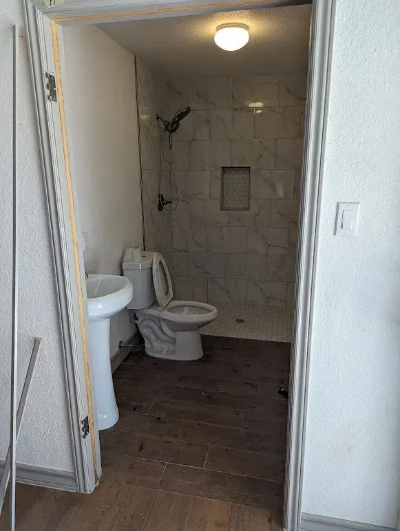 A bathroom with a toilet , sink and shower.