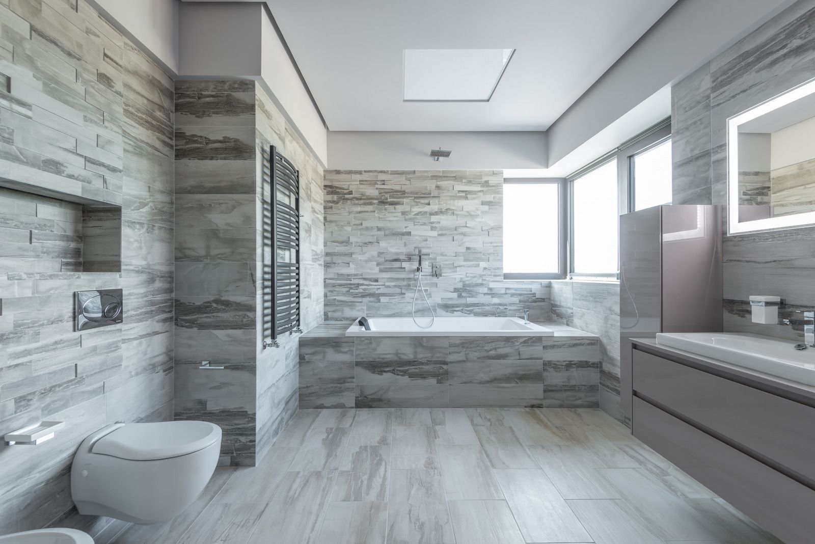 A bathroom with a black tile floor and a black counter top.