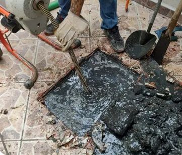 T&eacute;cnico extrayendo sarro de coladera en piso de mosaico