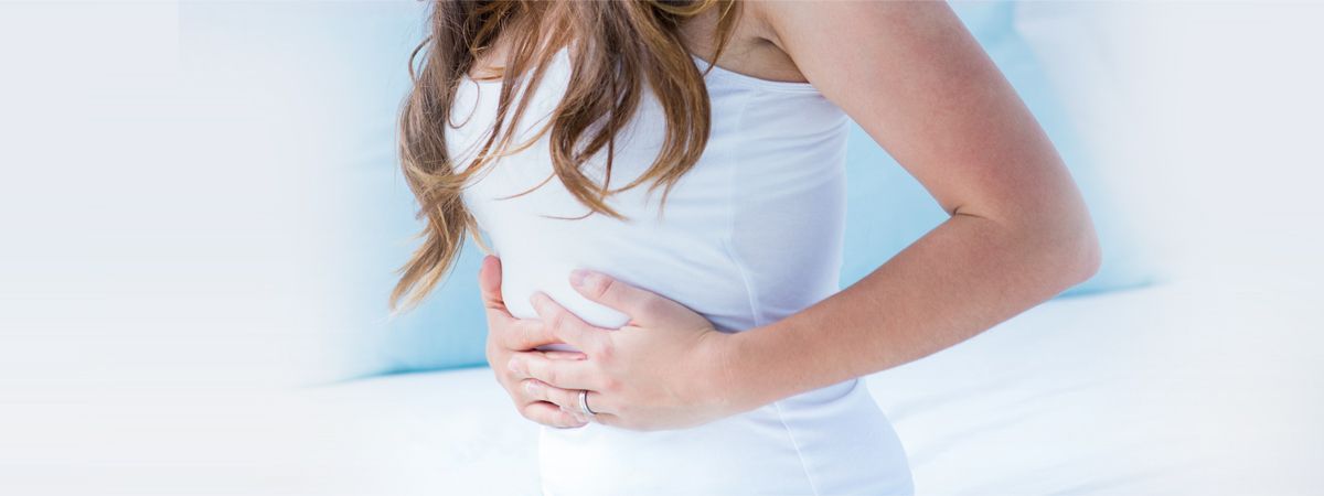 Woman holding her lower abdomen, concerned about irregular periods