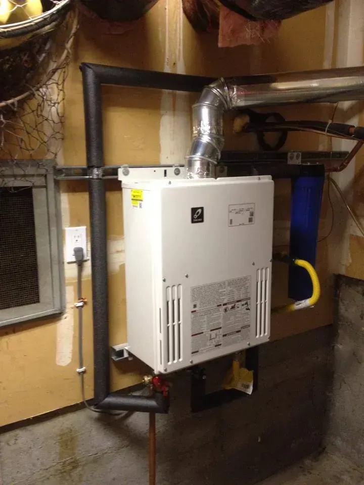 Wall-mounted white furnace with silver vent pipe and yellow gas line in a basement utility room