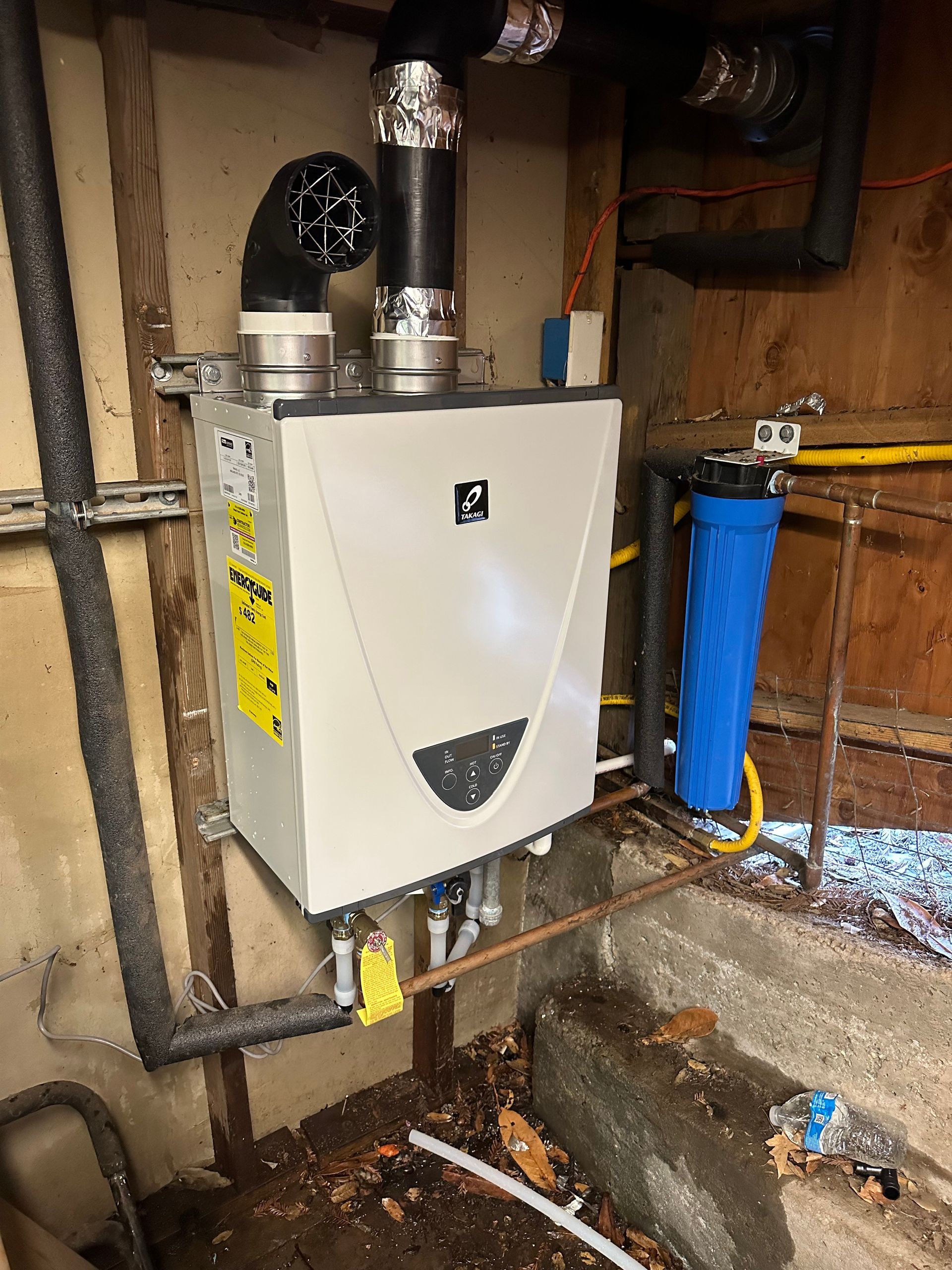 Wall-mounted boiler unit with pipes and vents in a basement utility area.