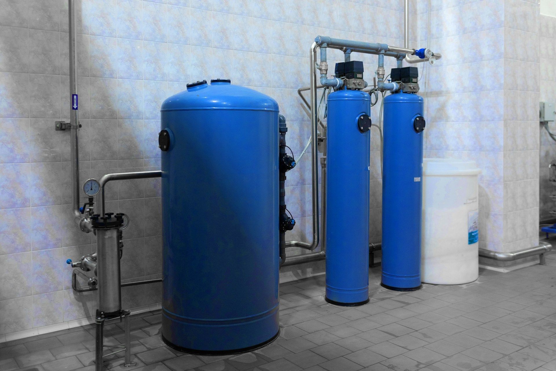 Blue water treatment tanks and pipes in an industrial room